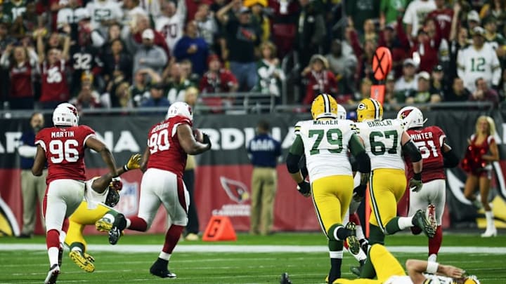 Dec 27, 2015; Glendale, AZ, USA; Green Bay Packers quarterback Aaron Rodgers (12) lies on the field as Arizona Cardinals defensive end Cory Redding (90) returns his fumble for a touchdown during the second half at University of Phoenix Stadium. Mandatory Credit: Joe Camporeale-USA TODAY Sports