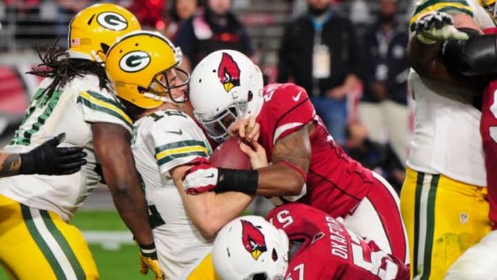 Dec 27, 2015; Glendale, AZ, USA; Green Bay Packers quarterback Aaron Rodgers (12) loses his helmet while being sacked by Arizona Cardinals outside linebacker Alex Okafor (57) and cornerback Jerraud Powers (25) during the second half at University of Phoenix Stadium. Mandatory Credit: Matt Kartozian-USA TODAY Sports