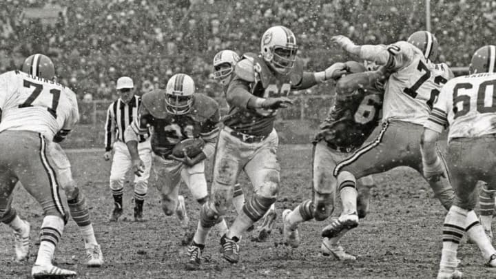CLEVELAND, OH - NOVEMBER 28: (EDITORS NOTE: Image has been shot in black and white. Color version not available.) Running back Norm Bulaich #31 of the Miami Dolphins runs behind the blocking of center Jim Langer #62 and guard Bob Kuechenberg #67 as defensive linemen Walter Johnson #71 and Jerry Sherk #72 and linebacker Bob Babich #60 of the Cleveland Browns pursue the play as snow falls during a game at Cleveland Municipal Stadium on November 28, 1976 in Cleveland, Ohio. The Browns defeated the Dolphins 17-13. (Photo by George Gojkovich/Getty Images)