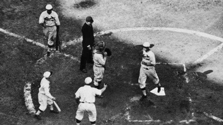 American baseball player infielder Andy High (1897 - 1981) of the St. Louis Cardinals (third from left) raises a hand to greet teammate outfielder George Watkins (1900 - 1970) as he comes across home plate after hitting a home run during game seven of the 1931 World Series against the Philadelphia Athletics, Sportsman's Park IV, St. Louis, October 10, 1931. The Cardinals won the game 4-2 to take the series. (Photo by Hulton Archive/Getty Images)