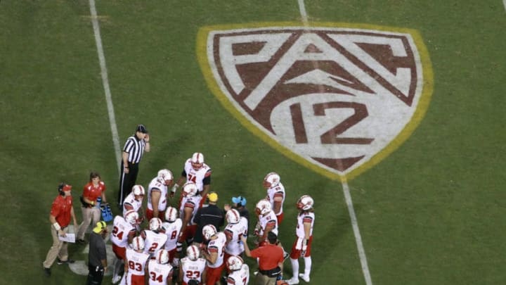 TEMPE, AZ - NOVEMBER 01: Utah Utes players gather near the Pac 12 logo during a timeout of a college football game against the Arizona State Sun Devils at Sun Devil Stadium on November 1, 2014 in Tempe, Arizona. (Photo by Ralph Freso/Getty Images)