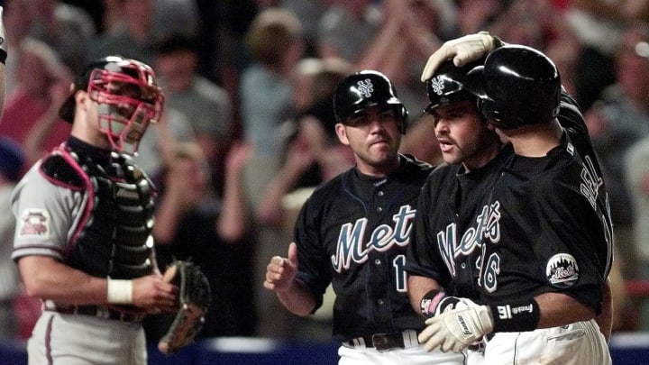 New York Mets catcher Mike Piazza (2nd R) is congratulated by teammates Edgardo Alfonso (L) and Derek Bell (R) after he drove the two men in with a three-run homer over the left field wall in the bottom of the eighth inning that put the Mets ahead 11-8 against the Atlanta Braves 30 June 2000 at Shea Stadium in Flushing, NY. The Mets scored 10 runs in the inning tieing a team record as they came from behind to beat the Braves 11-8.(ELECTRONIC IMAGE) AFP PHOTO/Matt CAMPBELL (Photo by MATT CAMPBELL / AFP) (Photo credit should read MATT CAMPBELL/AFP via Getty Images)
