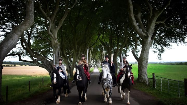 ANTRIM, NORTHERN IRELAND - AUGUST 29: Four actors on horseback dressed in Game of Thrones related costumes carry the Queen's Baton as they make their way way along the Dark Hedges on August 29, 2017 in Antrim, Northern Ireland. The Dark Hedges near Stranocum in County Antrim featured as the King's Road in season two of Game of Thrones and has become a tourist mecca for fans of the television series along with other filming locations in the province. The Queen's Baton Relay is currently on a tour of the United Kingdom as it makes its way around Europe in preparation for the 2018 Commonwealth Games in Australia. (Photo by Charles McQuillan/Getty Images)