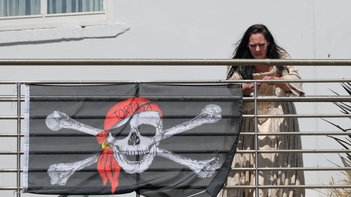 WHITBY, ENGLAND – JULY 06: A woman attaches a Jolly Roger pirate flag to the railings of a pub during the first day of the Whitby Captain Cook Festival on 6 July, 2018 in Whitby, England. The 3-day festival marks the 250th anniversary of James Cook’s first voyage aboard HM Bark Endeavour to the then-unchartered Southern Seas, today New Zealand and Australia. Captain Cook was born in Marton near Middlesbrough and moved to Whitby as an apprentice with a shipping firm. Later he joined the Royal Navy rising through the ratings to become a Captain. His famous ship HM Bark Endeavour was built in Whitby. (Photo by Ian Forsyth/Getty Images)
