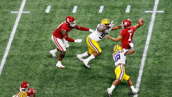 ATLANTA, GEORGIA - DECEMBER 28: Quarterback Jalen Hurts #1 of the Oklahoma Sooners is tackled by defensive end Glen Logan #97 and linebacker K'Lavon Chaisson #18 of the LSU Tigers during the Chick-fil-A Peach Bowl at Mercedes-Benz Stadium on December 28, 2019 in Atlanta, Georgia. (Photo by Mike Zarrilli/Getty Images)