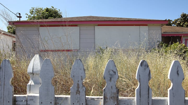 RICHMOND, CA – JUNE 14: Weeds grow past the height of a picket fence in front of an abandoned house on June 14, 2012 in Richmond, California. (Photo by Justin Sullivan/Getty Images)