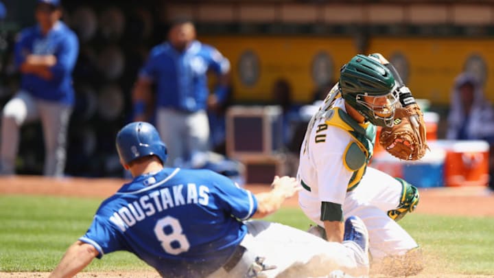 OAKLAND, CA - AUGUST 16: Mike Moustakas #8 of the Kansas City Royals slides safely into home plate past catcher Dustin Garneau #12 of the Oakland Athletics to score in the fifth inning at Oakland Alameda Coliseum on August 16, 2017 in Oakland, California. (Photo by Ezra Shaw/Getty Images)