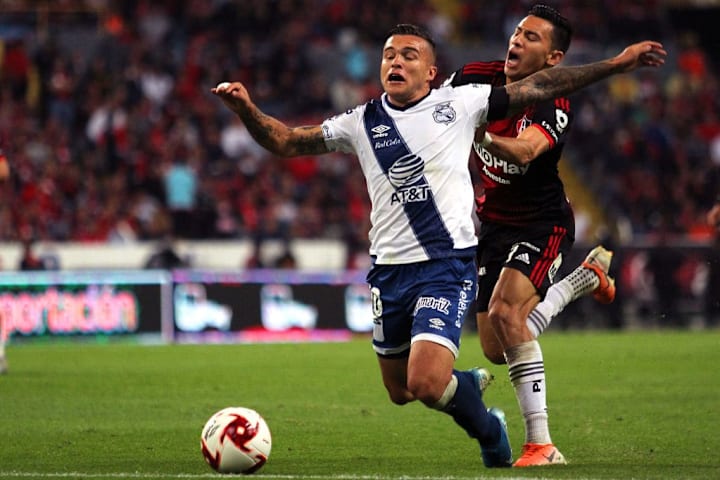 Jugadores de Atlas y Puebla pelean por un balón.
