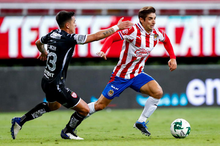 Isaac Brizuela controla el balón ante la marca de un jugador de Necaxa.
