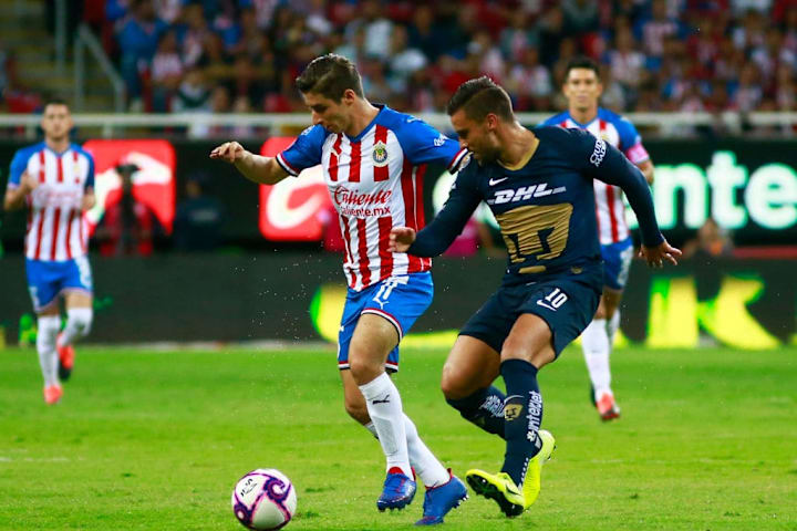 Isaac Brizuela cubre el balón ante la marca de un jugador de los Pumas UNAM.