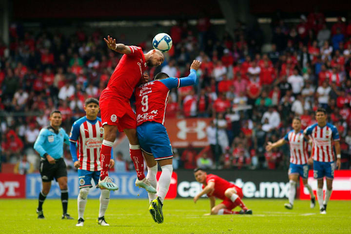 Jonatan Maidana pelea un balón por los aires con Alexis Vega, en partido entre Toluca y Chivas del Guadalajara.