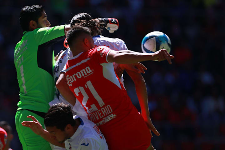 Jugadores de Toluca y Cruz Azul pelean un balón por los aires.