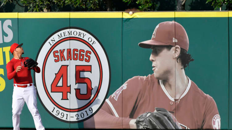 ANAHEIM, CA - SEPTEMBER 27: Hansel Robles #57 of the Los Angeles Angels looks at a ball as it goes over the wall and a photo of Tyler Skaggs #45 during batting practice before playing the Houston Astros at Angel Stadium of Anaheim on September 27, 2019 in Anaheim, California. (Photo by John McCoy/Getty Images)