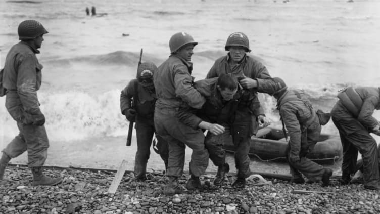 American troops helping their injured friends from a dinghy after the landing ship they were on was hit by enemy fire during the Allied invasion of France on D-Day
