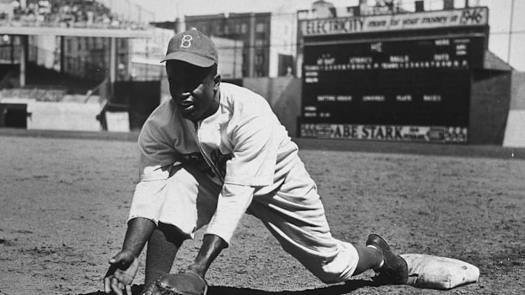 American baseball player Jackie Robinson (1919 - 1972) grounds a ball at first place while warming up for an exhibition game against the New York Yankees, Ebbets Field, NYC, 1950s. (Photo by Hulton|Archive/Getty Images)