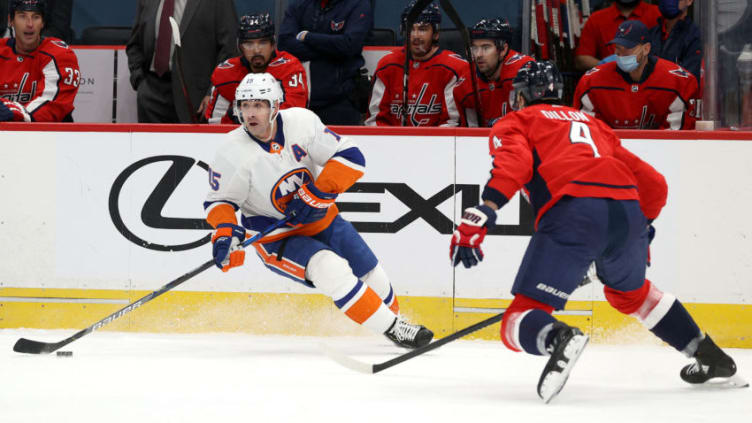 WASHINGTON, DC - JANUARY 28: Cal Clutterbuck #15 of the New York Islanders moves the puck against Brenden Dillon #4 of the Washington Capitals at Capital One Arena on January 28, 2021 in Washington, DC. (Photo by Rob Carr/Getty Images)