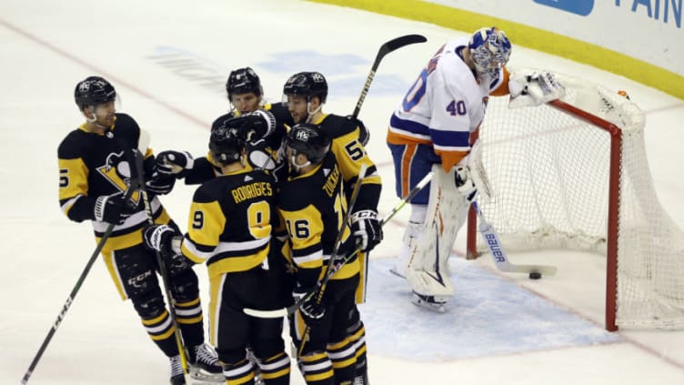 Mar 29, 2021; Pittsburgh, Pennsylvania, USA; The Pittsburgh Penguins celebrate after a goal by right wing Anthony Angello (57) as New York Islanders goaltender Semyon Varlamov (40) retrieves the puck from the net during the first period at PPG Paints Arena. Mandatory Credit: Charles LeClaire-USA TODAY Sports