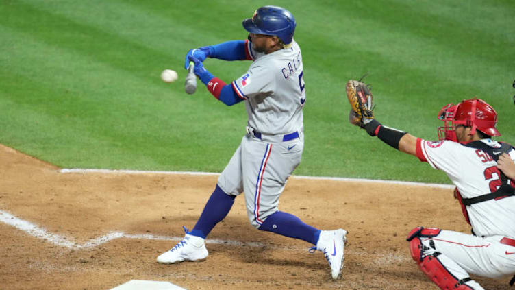 Apr 19, 2021; Anaheim, California, USA; Texas Rangers left fielder Willie Calhoun (5) follows through on a run-scoring single in the sixth inning as Los Angeles Angels catcher Kurt Suzuki (24) watches at Angel Stadium. Mandatory Credit: Kirby Lee-USA TODAY Sports