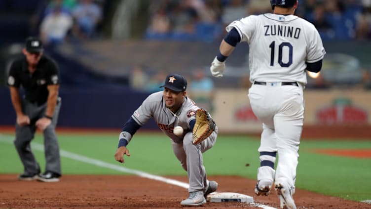 ST. PETERSBURG, FL - MARCH 29: Yuli Gurriel #10 of the Houston Astros reaches for a throw that pulled him off the base and lead to Mike Zunino #10 of the Tampa Bay Rays being safe at first base in the third inning of a baseball game at Tropicana Field on March 29, 2019 in St. Petersburg, Florida. (Photo by Mike Carlson/Getty Images)