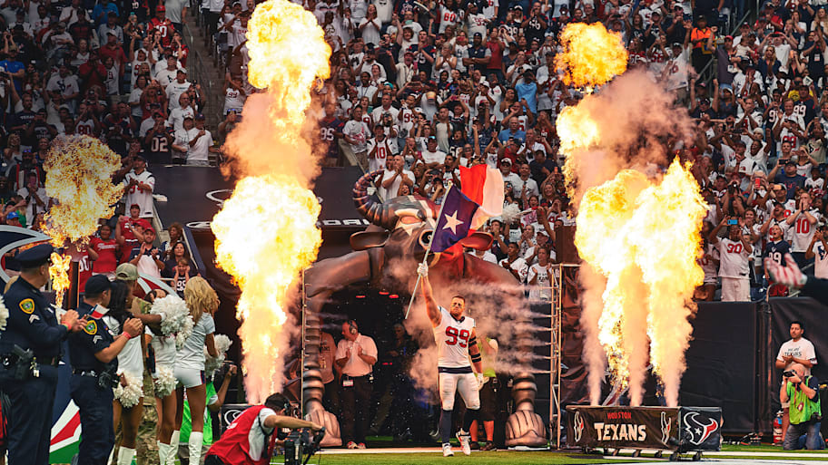J.J. Watt runs onto the field holding a flag.