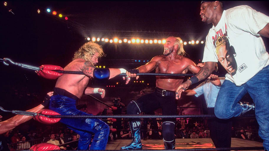 Hulk Hogan lays into Diamond Dallas Page in the corner of the ring while tag team partner Dennis Rodman eggs him on.