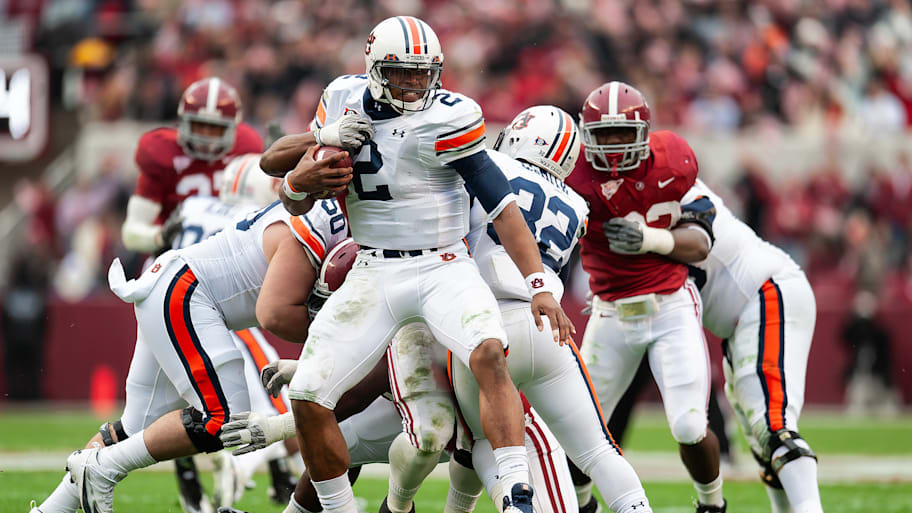 Cam Newton attempts to escape a tackle by Alabama defenders in 2010.