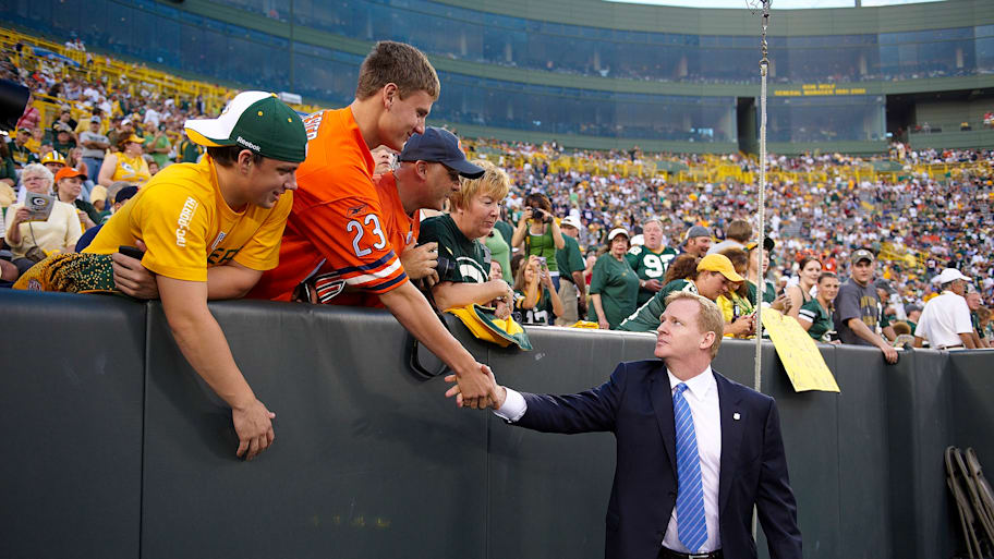 Roger Goodell reaches into the stands to shake a fan's hand.