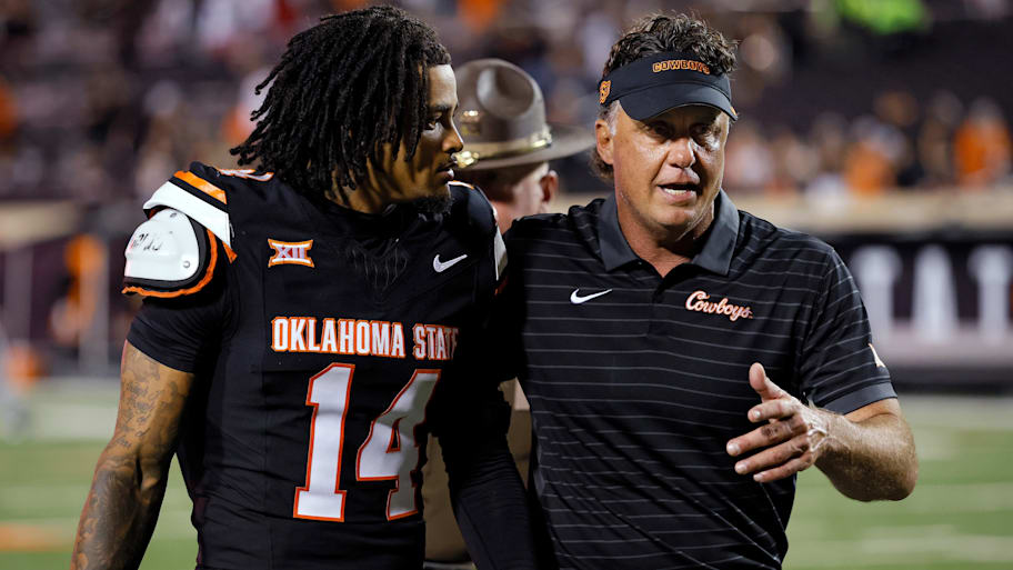 Oklahoma State head coach Mike Gundy speaks with safety Landyn Cleveland while walking off the field.