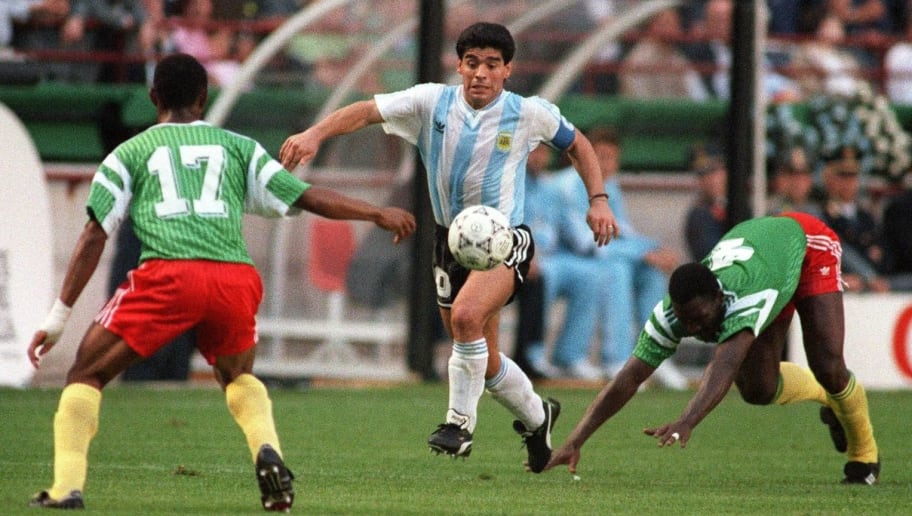 Argentinian forward Diego Maradona juggles with the ball as he runs past Cameroon's Benjamin Massing during the World Cup opening soccer match between Cameroon and Argentina 08 June 1990 in Milan. Cameroon upset the defending world champions 1-0.  (At left is Victor Ndip Akem)  AFP PHOTO/DANIEL GARCIA (Photo credit should read DANIEL GARCIA/AFP/Getty Images)