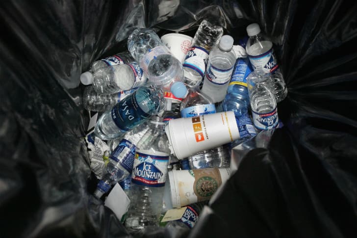 Water bottles sit in a garbage bin at an airport