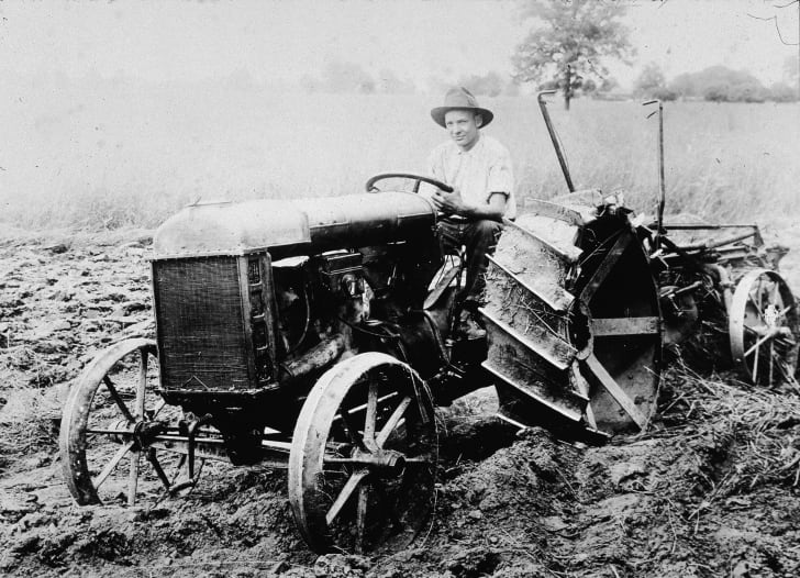 A man sits in the driver seat of the first Ford tractor, circa 1920.