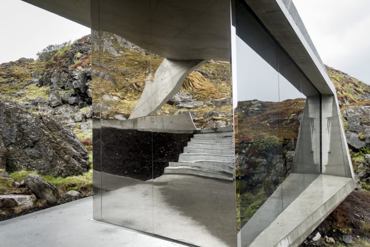 The mirrored facade of a rest stop reflects concrete steps leading down a pathway.