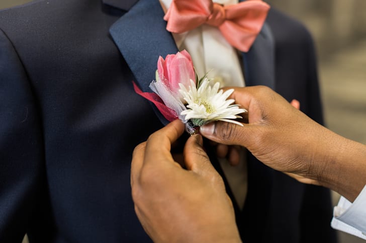 A boy pins a boutonniere to a tux lapel