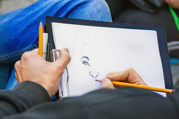 Man's hands with pencils drawing a woman's portrait