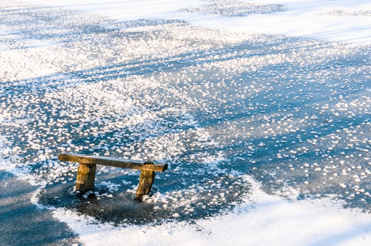 A pond covered in a thin layer of ice and snow.