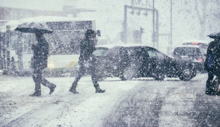 Pedestrians and cars in the snow.