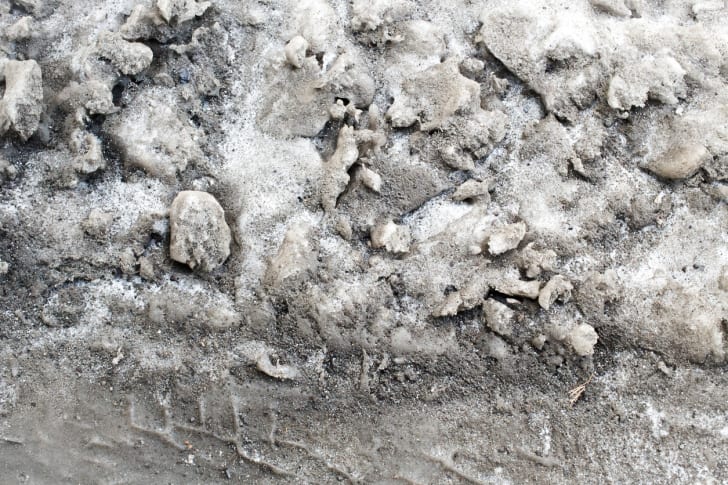 Dirty snow marked with tire tracks.