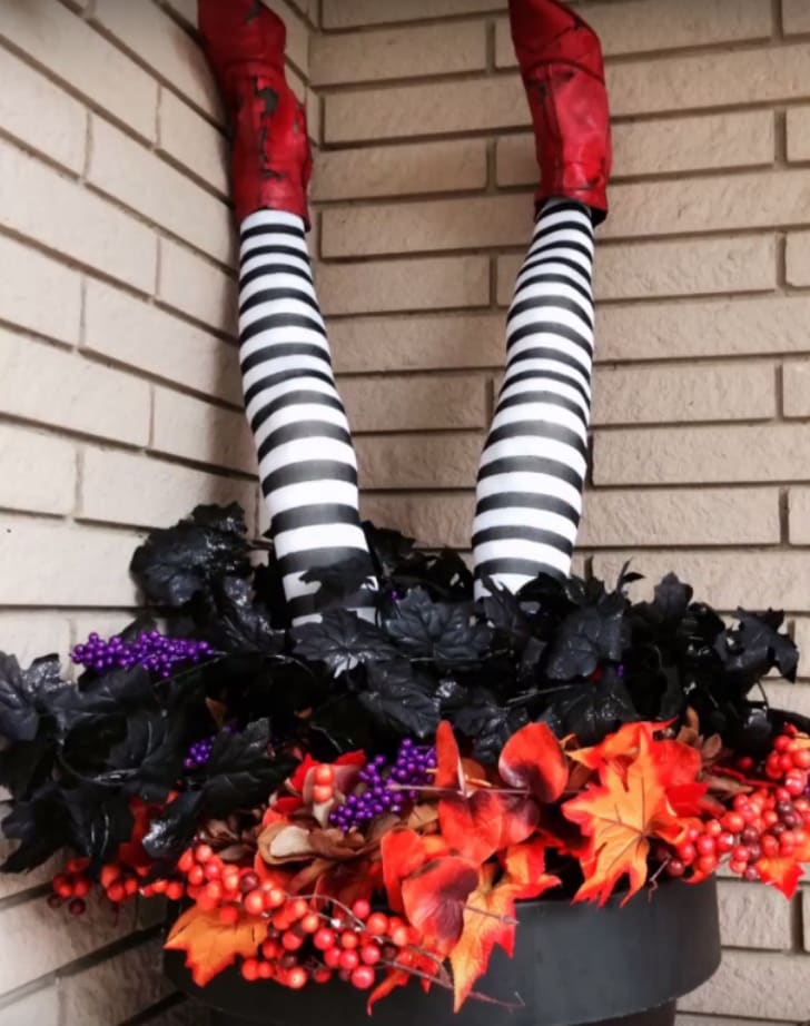 A pair of pool noodle witch legs stick out from a planter