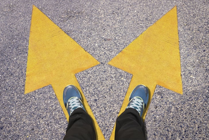 A pair of blue shoes on the ground with yellow arrows pointing in two different directions
