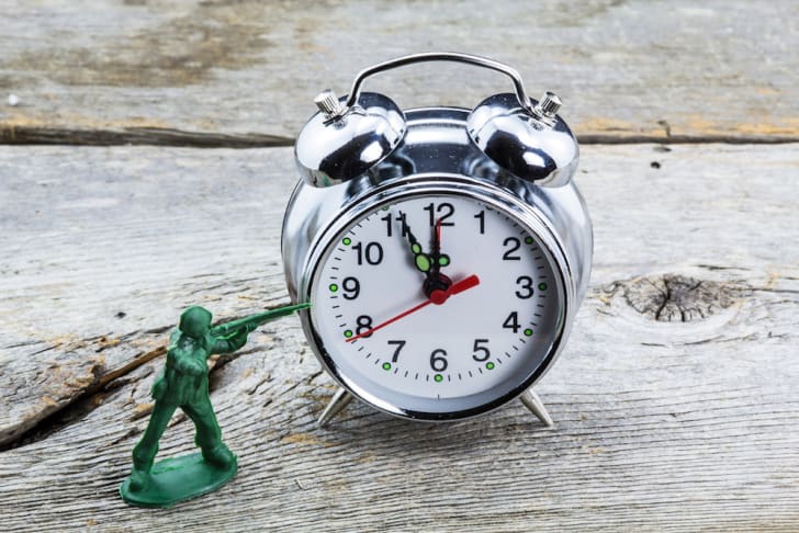 Photo of a toy soldier aiming at an alarm clock