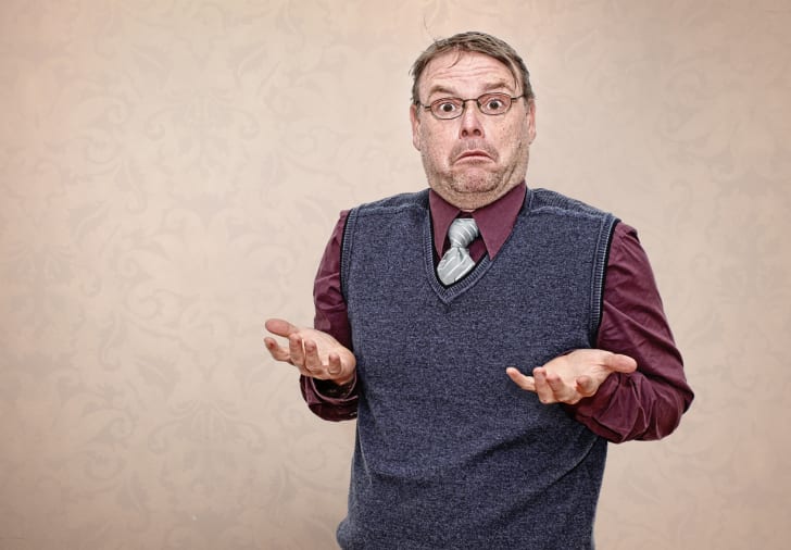 A man in a vest and tie shrugging.