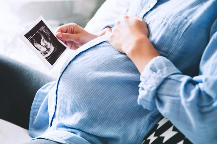 A pregnant woman sitting in a chair, looking at a sonogram.