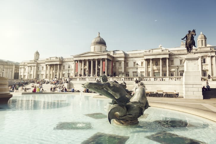 A fountain in front of a large columned building on Trafalgar Square