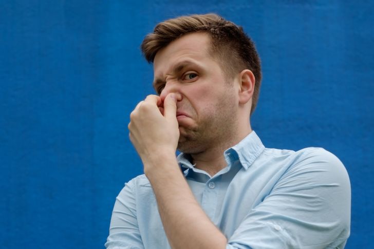 man holding his nose because of terrible smell