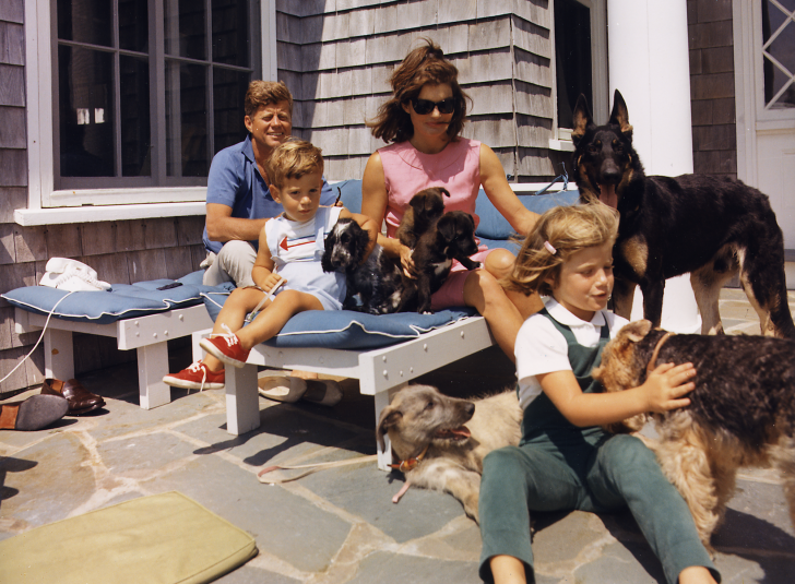 President Kennedy, John F. Kennedy Jr., Mrs. Kennedy, Caroline Kennedy. Dogs: Clipper ( standing ), Charlie ( with Caroline ), Wolf ( reclining ), Shannon ( with John Jr. ), two of Pushinka's puppies ( with Mrs. Kennedy ).