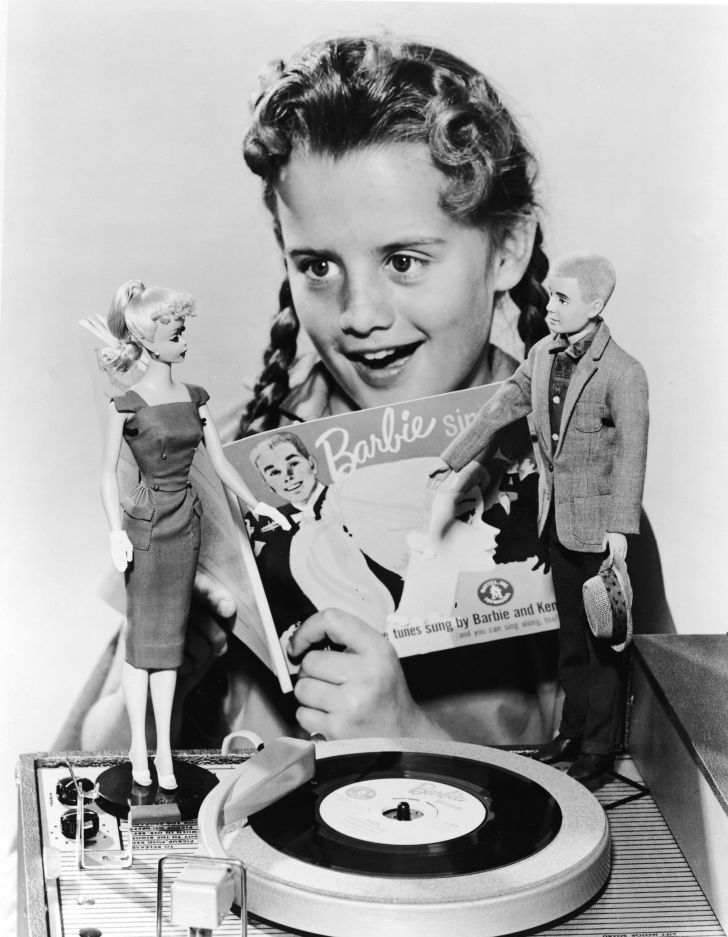 A girl plays with a Barbie and Ken doll in 1961.