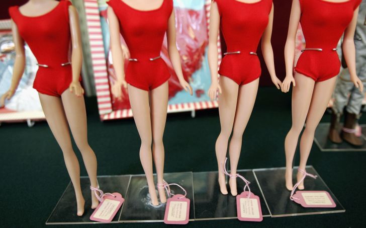 The waists of four Barbie dolls in red swimsuits