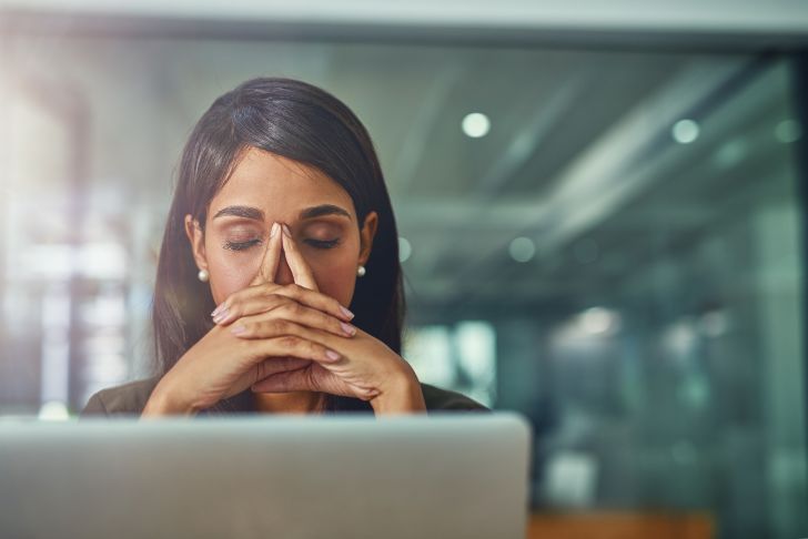 A woman sitting in front of a computer looking tired.
