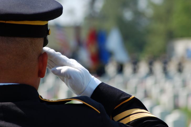 Soldier saluting in uniform in cemetery.