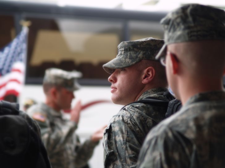 Military members in uniform waiting to board bus.